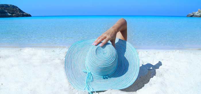 Mujer con sombrero en la playa ideando estrategia del oceáno azul