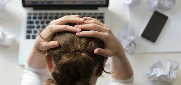 Empresaria se sujeta la cabeza frente a laptop