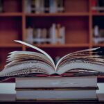 20 libros de liderazgo empresarial | Lecturas para ser un líder exitoso Libros sobre una mesa uno abierto fondo bilbioteca