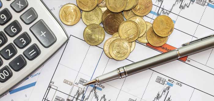 Monedas y bolígrafo con documentos de plan financiero