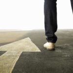 10 historias de personas exitosas | ¡De pobres a millonarios! flecha en el suelo y piernas caminando al lado, señalan el camino correcto hacia las historias de personas exitosas