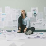 15 causas del fracaso del emprendedor | Evita ese efecto persona agobiada por el fracaso del emprendedor sentada en el suelo, rodeada de papeles