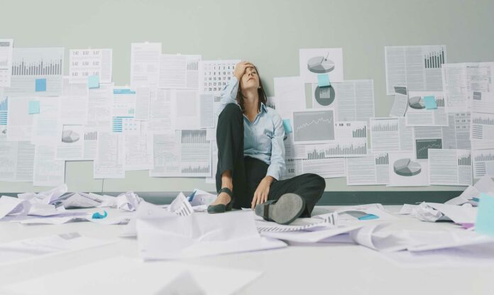 persona agobiada por el fracaso del emprendedor sentada en el suelo, rodeada de papeles