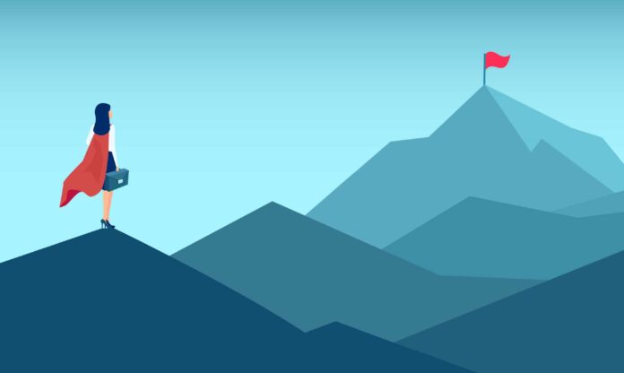 mujer con capamira en dirección al pico de una montaña en donde se encuentra una bandera roja, como símbolo de la visión empresarial