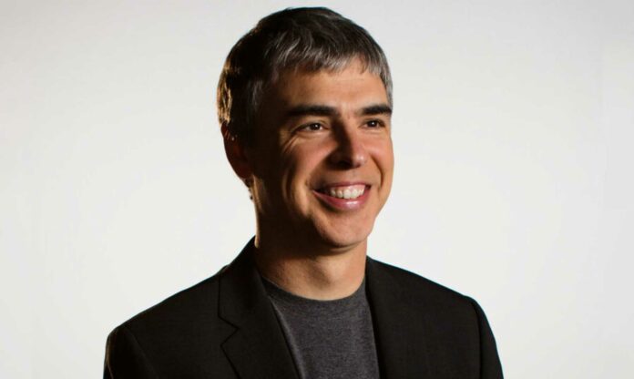 Larry Page sonriendo con traje negro y fondo gris