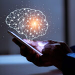 12 estrategias de neuromarketing para un producto | Impulsa tus ventas Persona con un teléfono móvil en su mano y el holograma de un cerebro en referencia al neuromarketing