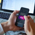Publicidad programática | Un paso adelante en las ventas personalizadas Persona con su móvil mirando una publicidad programática.